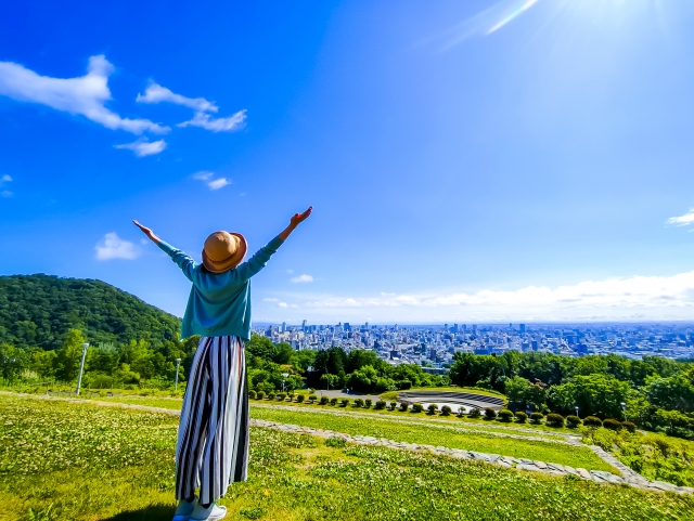富士山を背景に、湖畔で深呼吸する女性の後ろ姿。