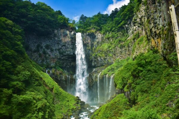 華厳ノ滝の壮大な景観。岩肌を流れ落ちる力強い滝と周りの緑が美しい