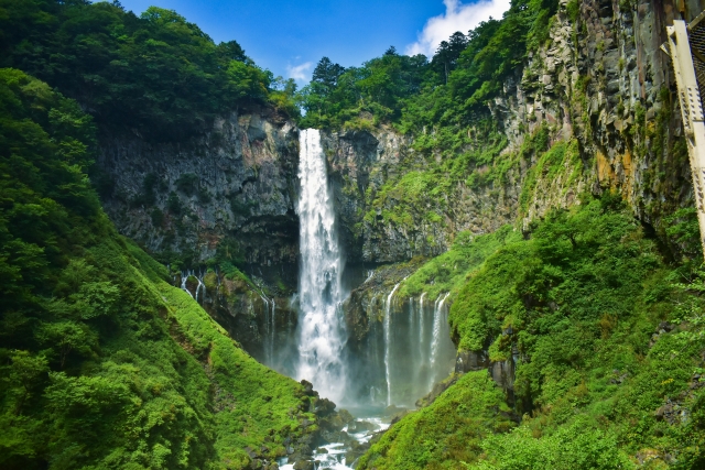 華厳ノ滝の壮大な景観。岩肌を流れ落ちる力強い滝と周りの緑が美しい