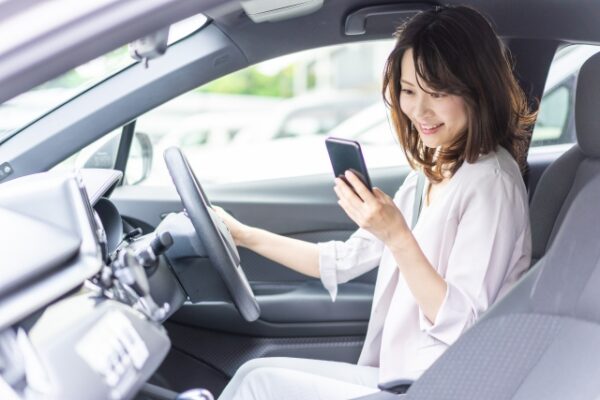 運転席でスマホのナビを確認している女性