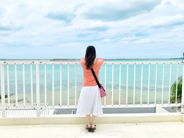 青空と海を見ている女性の後ろ姿