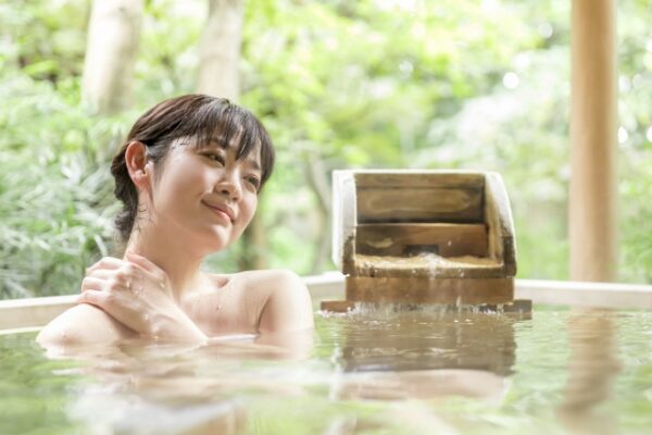 温泉露天風呂に浸かりリラックスしている女性